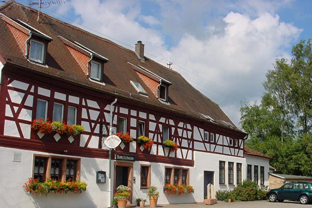 ein Gebäude mit Blumenkästen auf der Vorderseite in der Unterkunft Landgasthof & Hotel "Zum Schwan" GmbH in Trippstadt