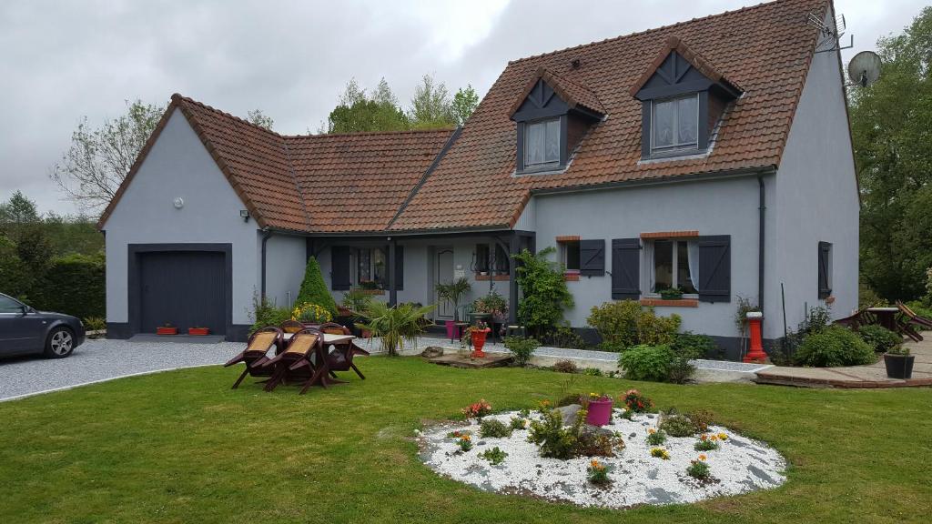 ein Haus mit einem Blumenbett im Hof in der Unterkunft Les Mésanges in Estréelles