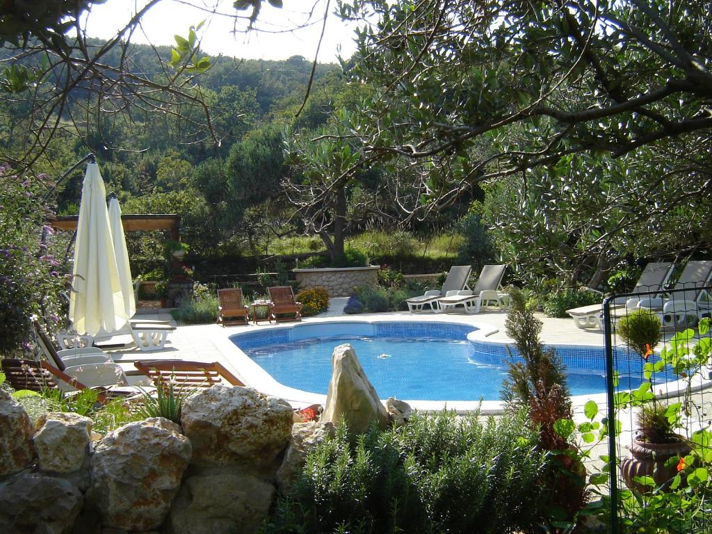 a swimming pool with chairs and an umbrella at Apartments Mirjana in Rab