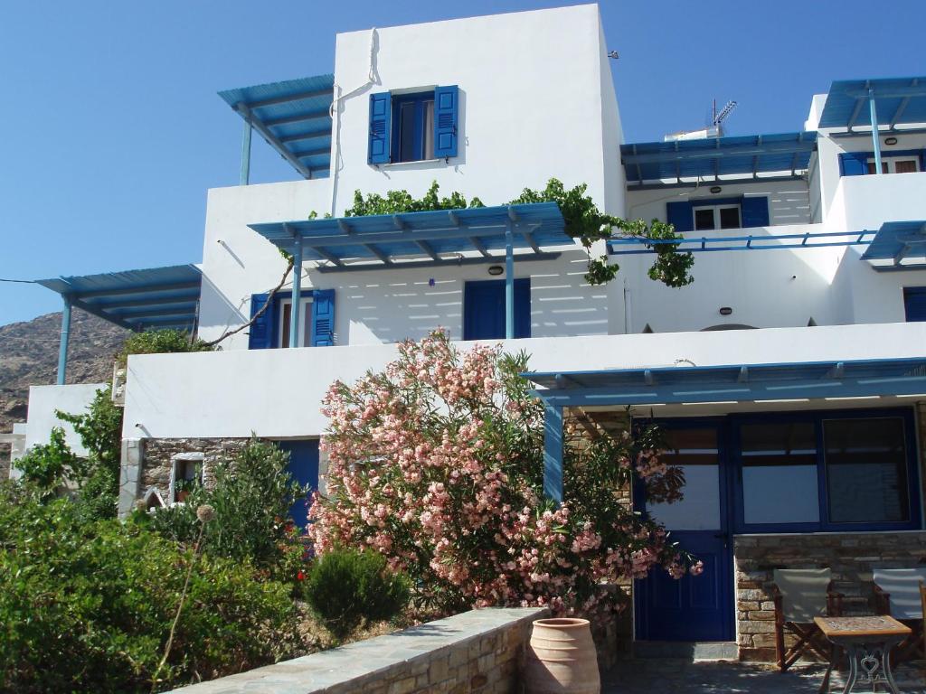 un edificio blanco con puertas azules y un árbol en Helena's Apartments, en Manganari