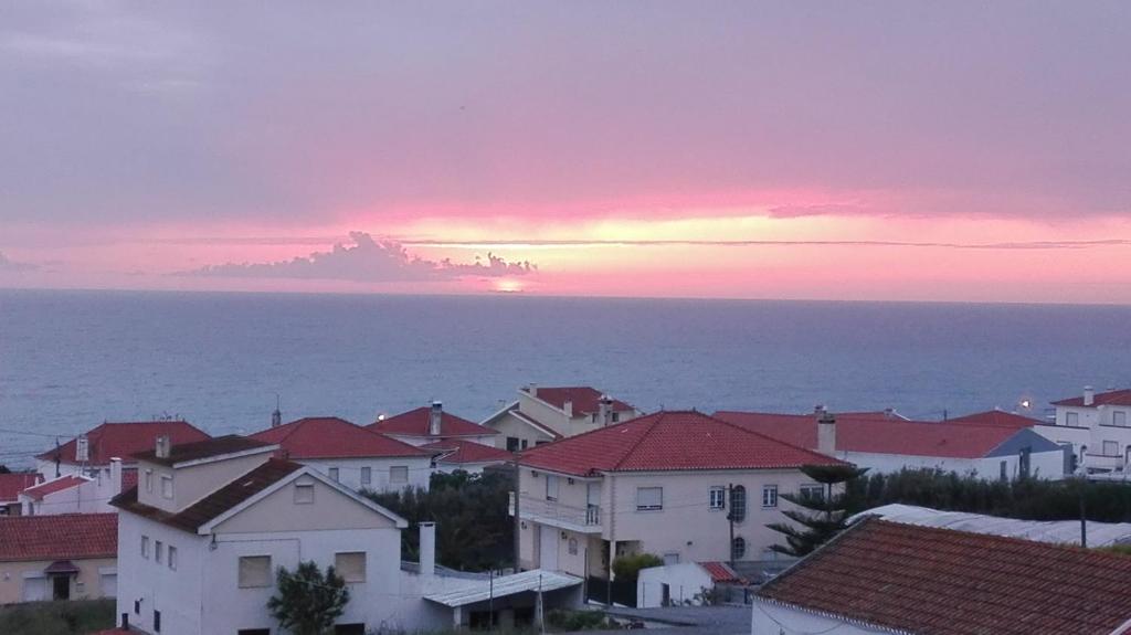 a sunset over a town with houses and the ocean at Casa das Conchas in Ericeira