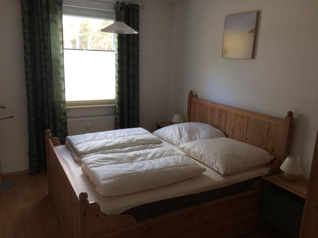 Schlafzimmer mit einem Bett mit weißer Bettwäsche und einem Fenster in der Unterkunft Wohnung Bernstein - Nr. 4 in Dierhagen