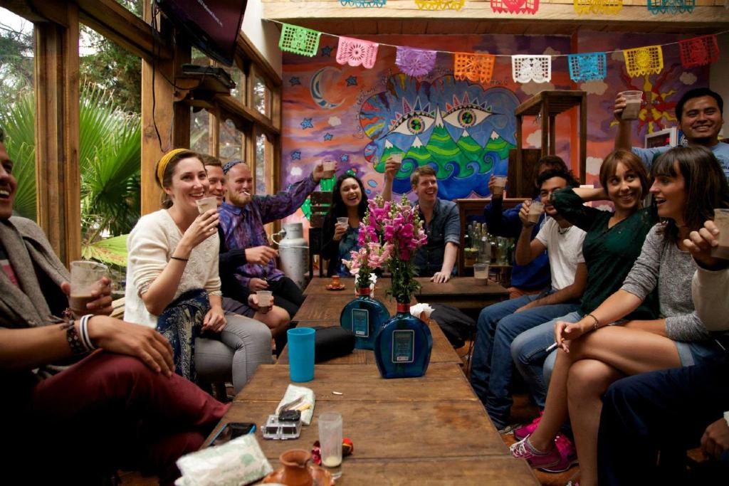 un grupo de personas sentadas alrededor de una mesa en un bar en Planet Hostel en San Cristóbal de Las Casas
