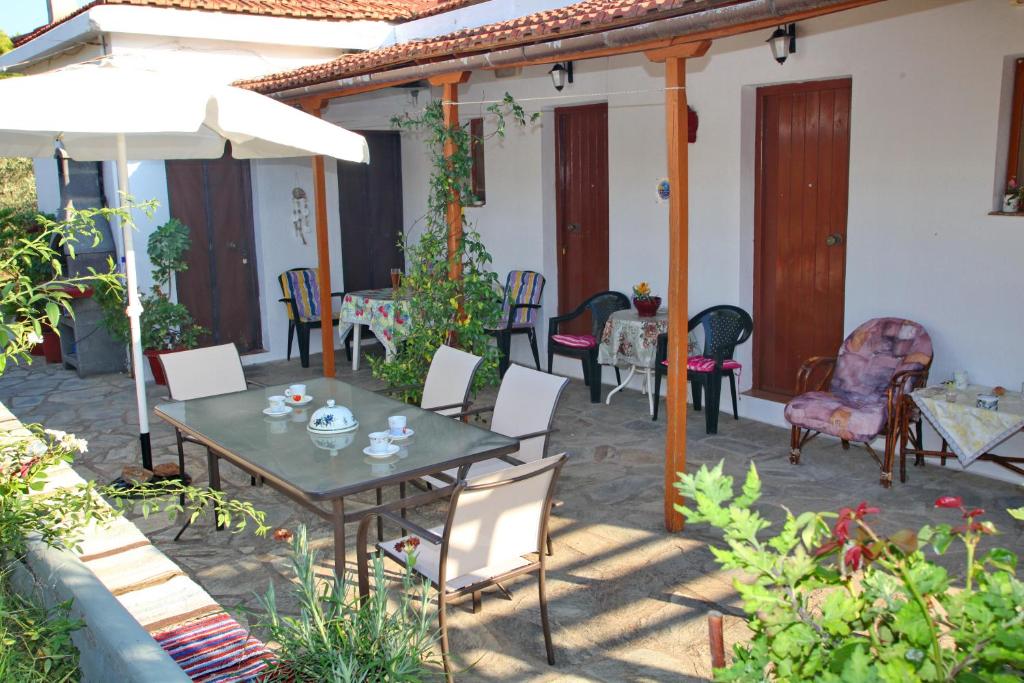 un patio con mesa, sillas y sombrilla en Armonia Guesthouse, en Panormos Skopelos