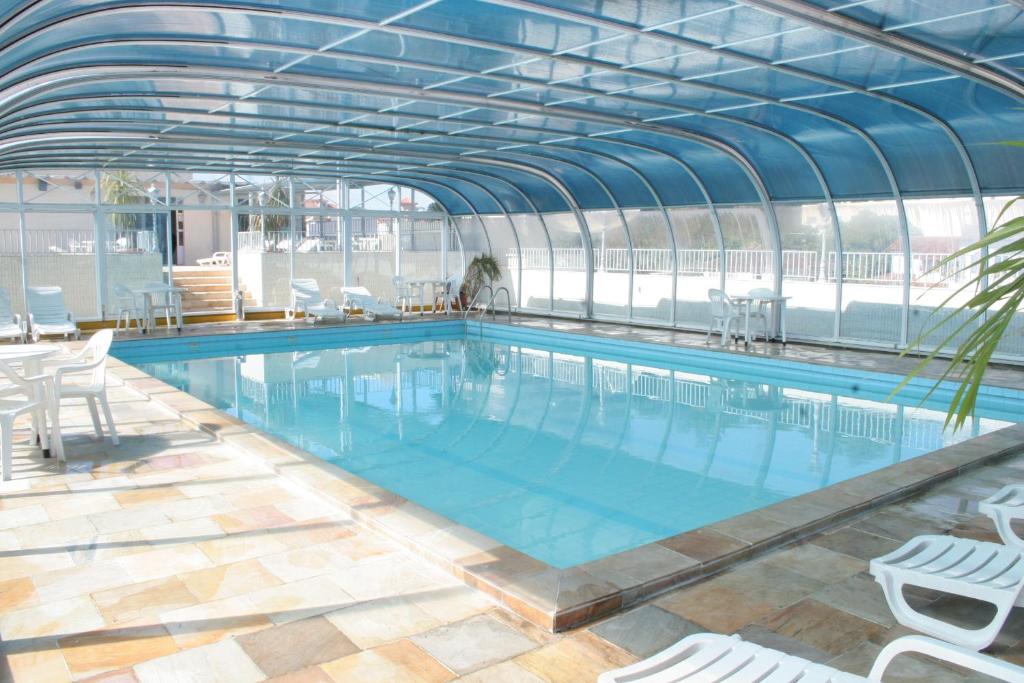 a large swimming pool with chairs and a building at Hotel Negreiros in São Lourenço