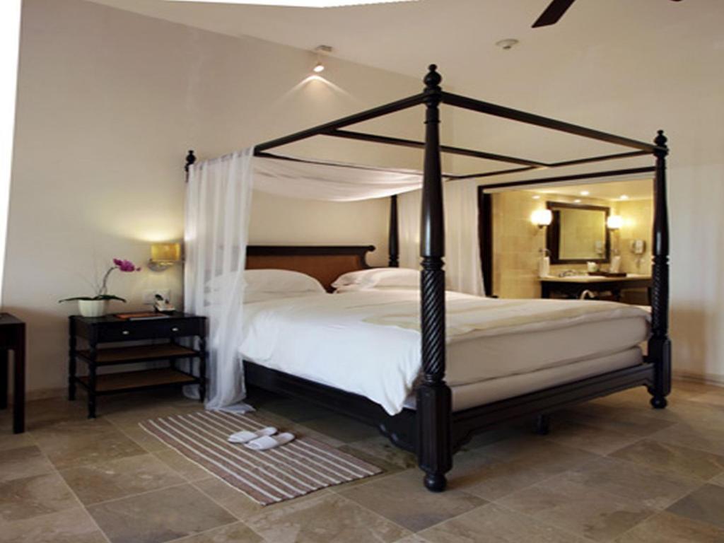 a bedroom with a canopy bed and a mirror at Casa Colonial Beach & Spa in San Felipe de Puerto Plata