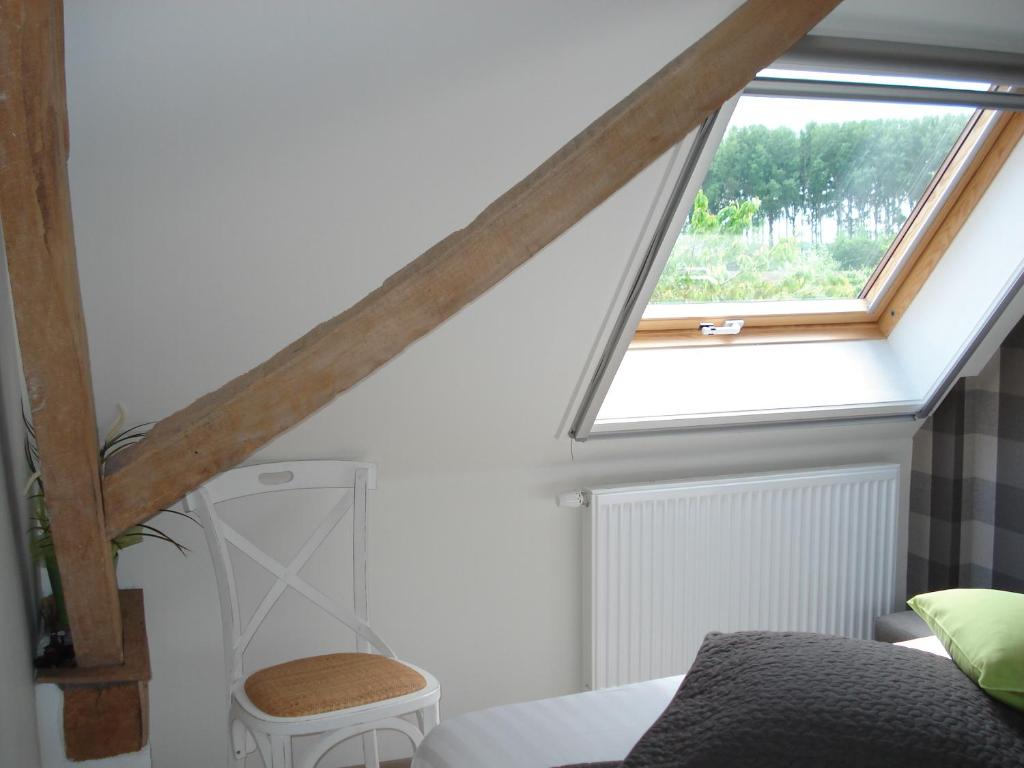 a attic room with a window and a chair at B&B Hoeve 't Geleed in Damme