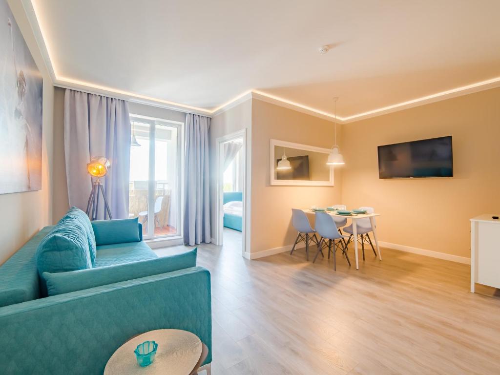 ein Wohnzimmer mit einem blauen Sofa und einem Tisch in der Unterkunft Apartament 617 w Hotelu Polonia in Kołobrzeg