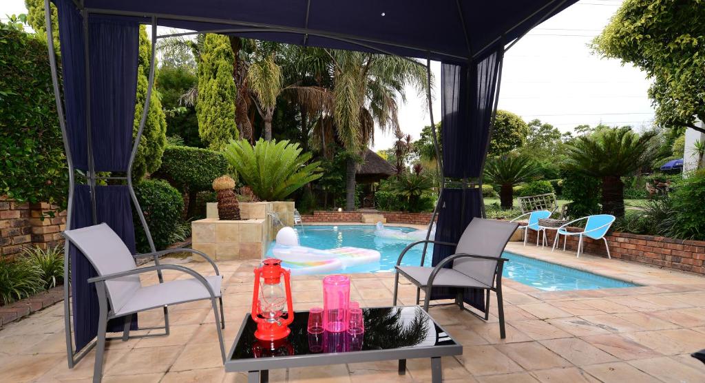 a pool with a gazebo and a table with drinks on it at Corgi Guest House in Johannesburg