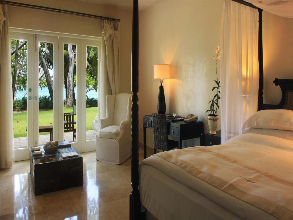 a bedroom with a bed and a chair and a window at Casa Colonial Beach & Spa in San Felipe de Puerto Plata