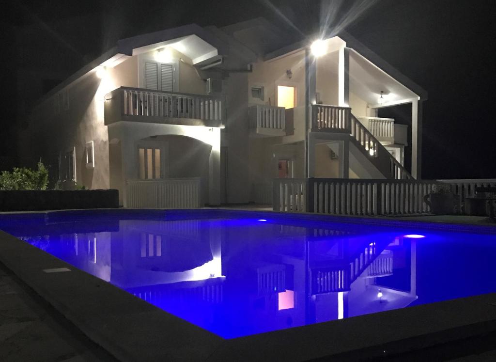 a swimming pool at night with a house in the background at Apartments Vila Lazarevic in Tivat