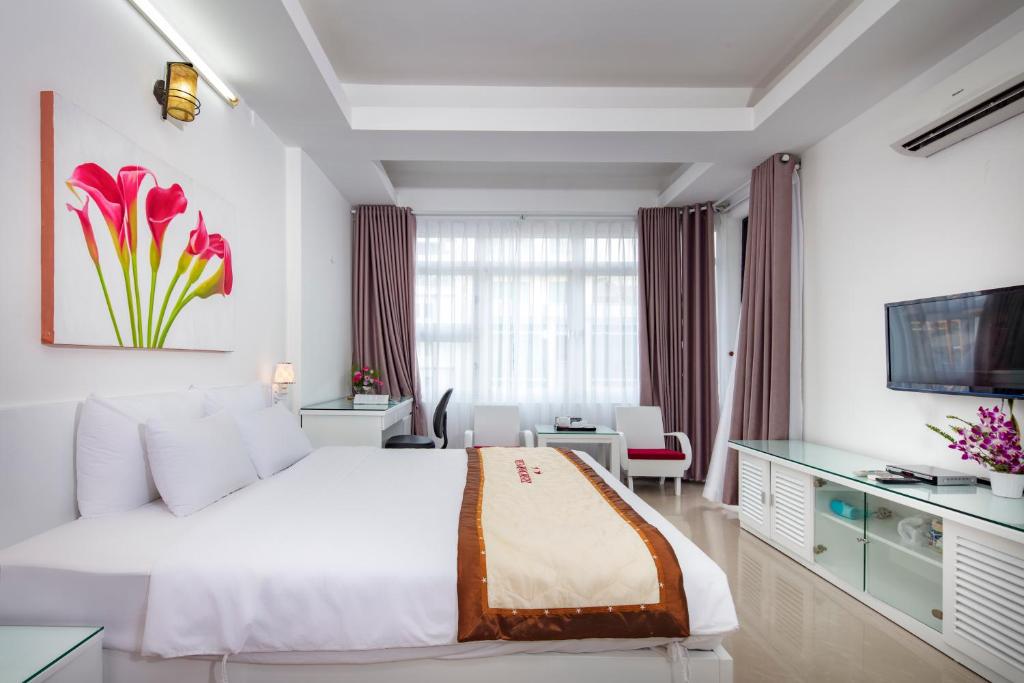 a bedroom with a large white bed and a desk at Vien Dong Hotel 3 in Ho Chi Minh City