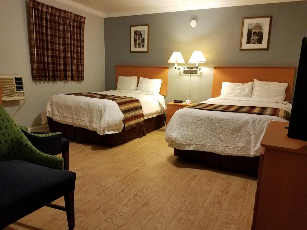 a hotel room with two beds and two lamps at Scottish Inn - Okeechobee in Okeechobee