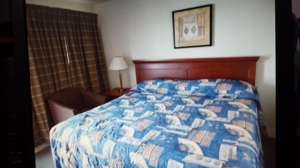 a bedroom with a bed with a blue and white quilt at Star Inn by Elevate Rooms in Niagara Falls