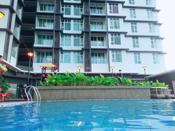 a swimming pool in front of a large building at Caliph Suite Apartment Homestay D'Perdana Sri Cemerlang Condominium Kota Bharu in Kota Bharu