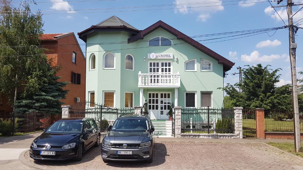 due auto parcheggiate di fronte a una casa di Guest House Luxotel a Zrenjanin