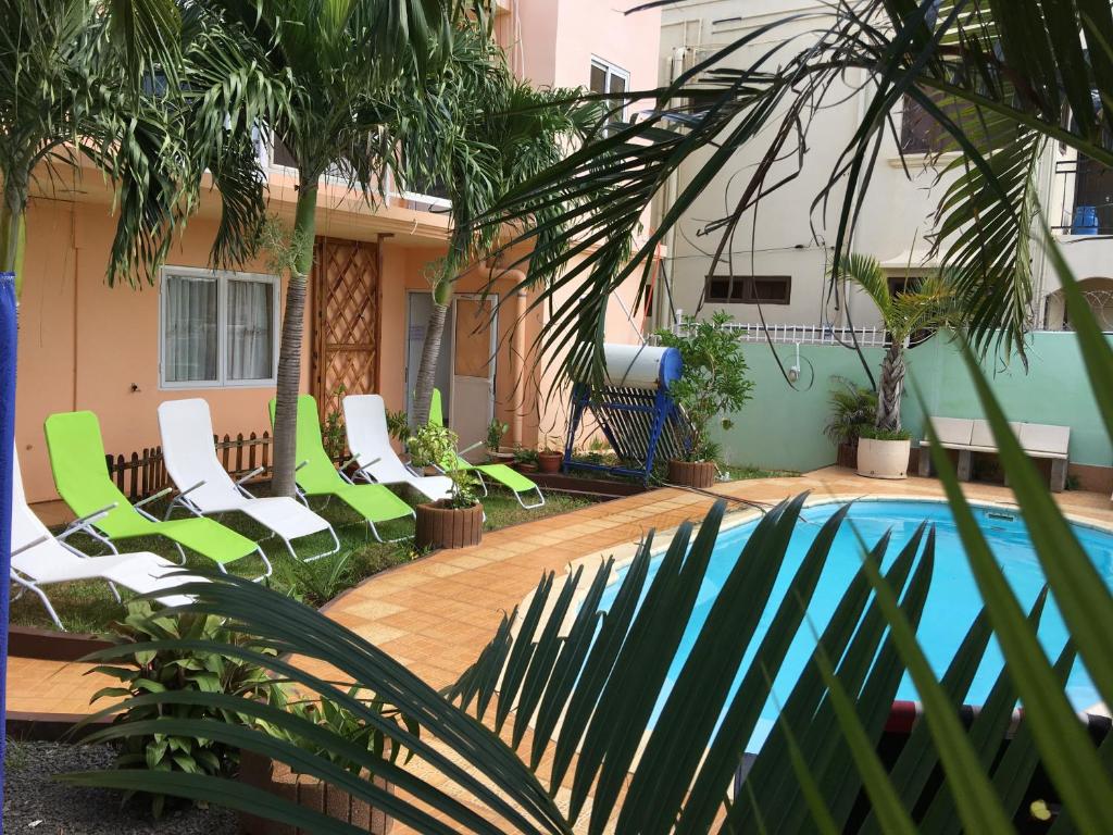 a group of green chairs next to a swimming pool at Sunshine Villa Mauritius in Flic-en-Flac