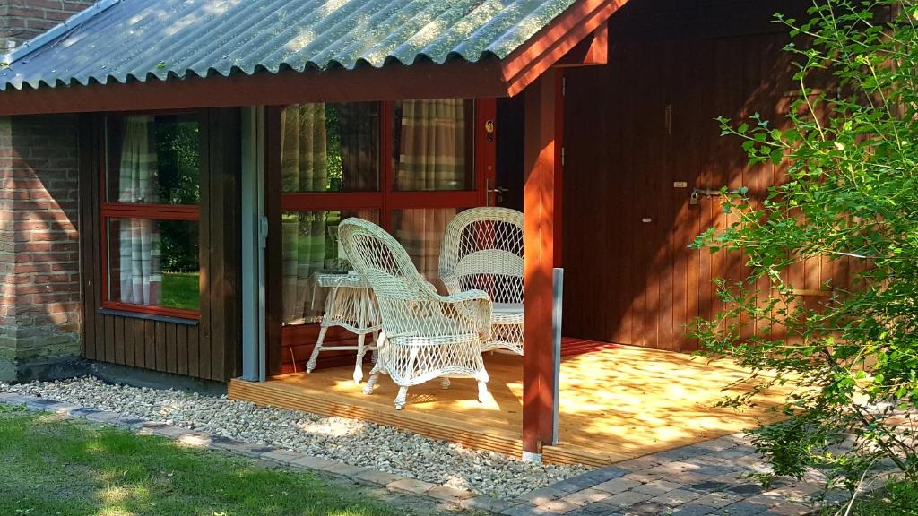 eine abgeschirmte Veranda mit 2 Korbstühlen darauf in der Unterkunft Lille Hus in Gartow