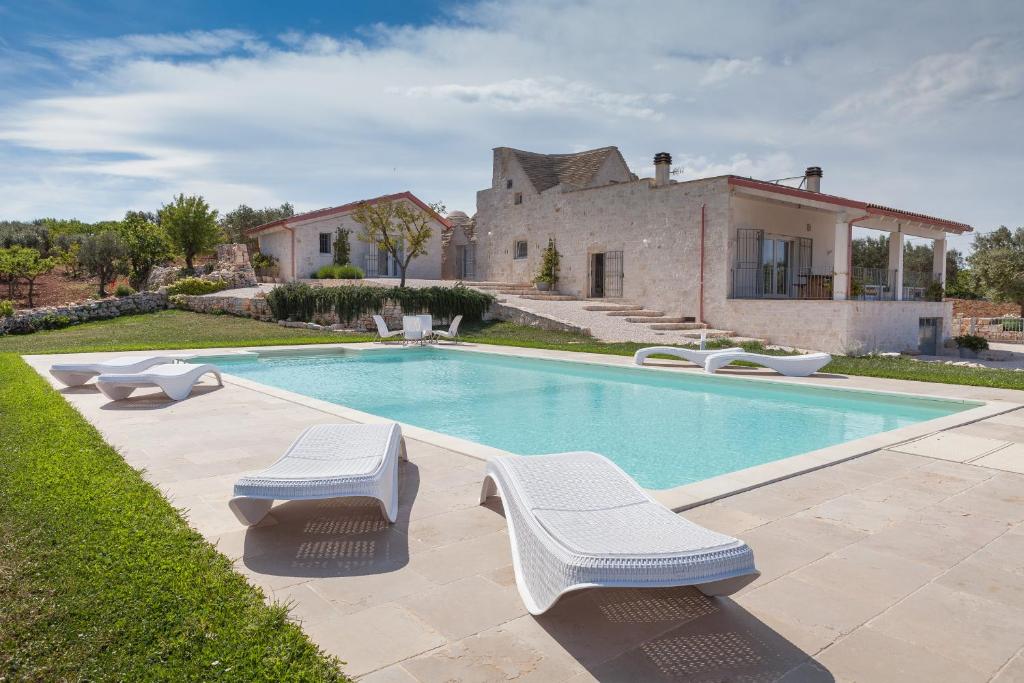 una piscina con 2 sillas y una casa en B&B A Casa di Pier, en Castellana Grotte