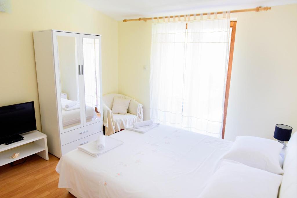 - une chambre avec un lit blanc et un miroir dans l'établissement Apartment ANA Podstrana, à Podstrana