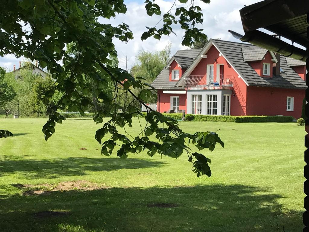 ein rotes Haus auf einem Feld mit einem grünen Hof in der Unterkunft Linden Garden Apartment in Postojna