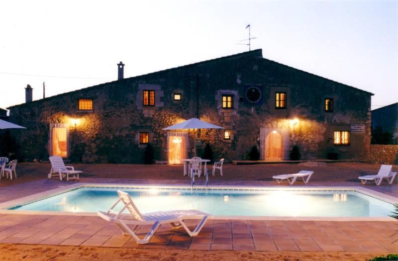 a swimming pool with two lawn chairs and a house at Mas Peraquintana in L'Escala