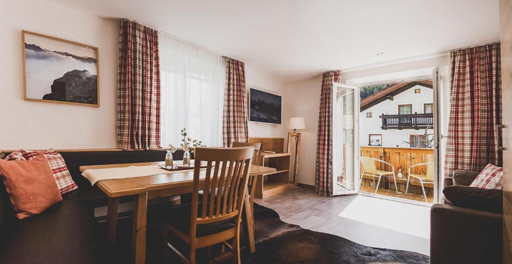 a living room with a dining room table and a room with a balcony at Hotel Montfort in Sankt Anton am Arlberg