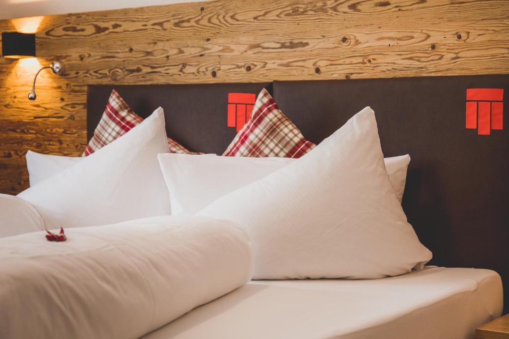 a bed with white pillows and a wooden headboard at Hotel Montfort in Sankt Anton am Arlberg