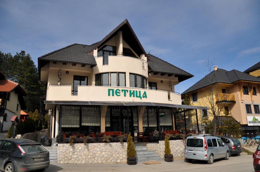 Un hotel con coches aparcados en un estacionamiento. en Apartmani Vidic, en Zlatibor
