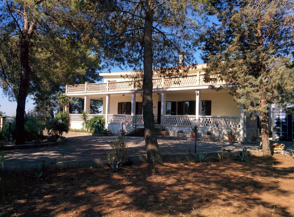 une grande maison blanche avec des arbres au premier plan dans l'établissement Villa 2 Fields, à Castellaneta