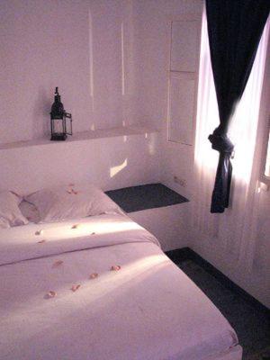 a white bedroom with a bed and a window at Maison Xanadu in Sidi Ifni