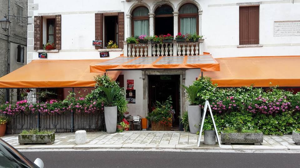 un edificio con un balcón con flores. en Ristorante Pizzeria al Mondo, en Valstagna