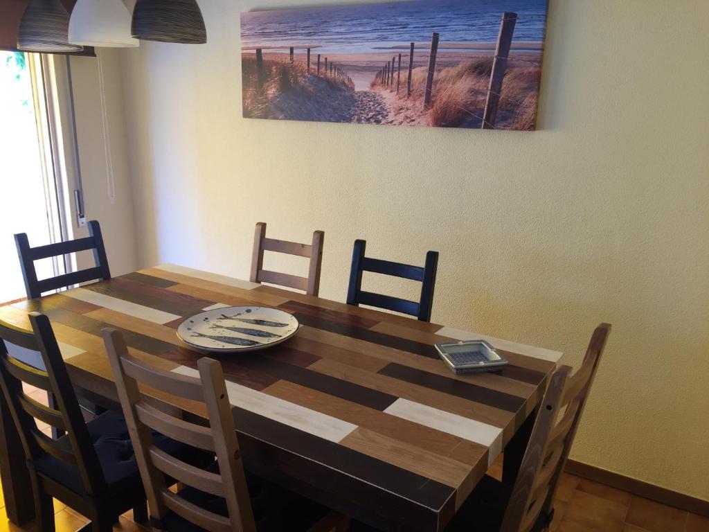 a dining room table with chairs and a painting on the wall at Tiagos Apartament in Faro