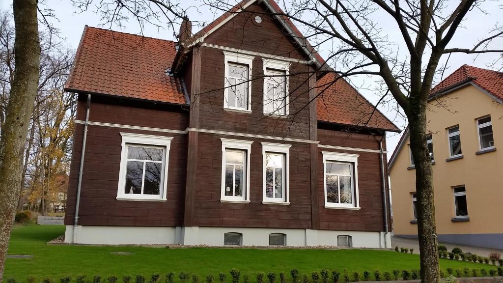 a large brown house with white windows and a tree at Ferienwohnung Parkblick in Soltau