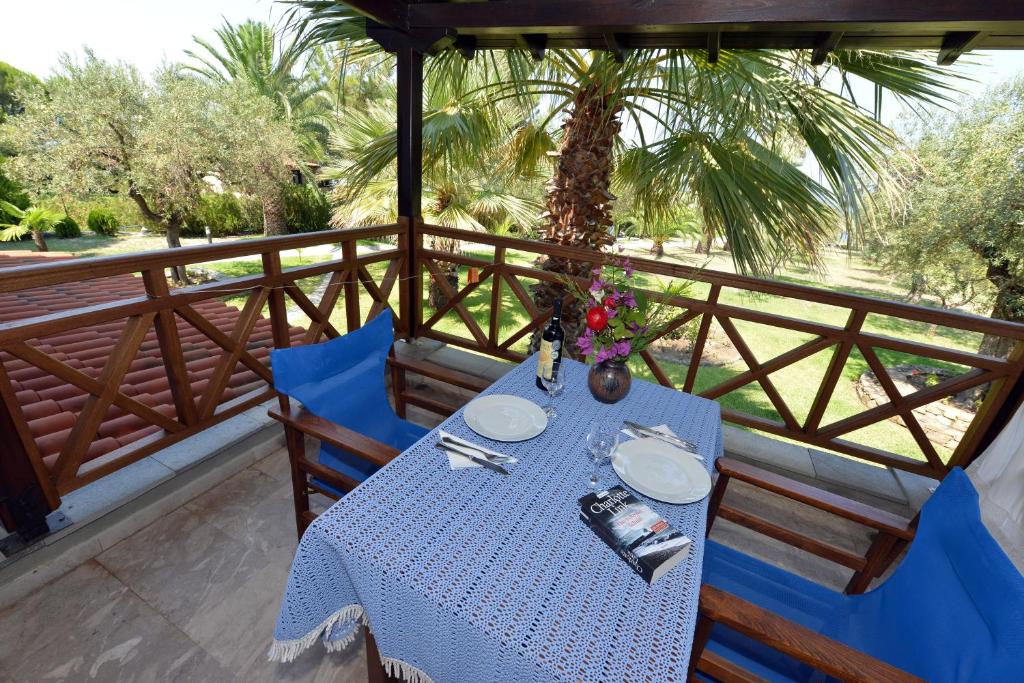 a table and chairs on a balcony with a palm tree at Haus Katerina in Vourvourou