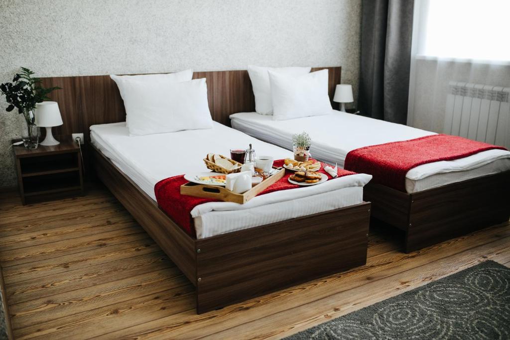 2 Betten in einem Hotelzimmer mit einem Tablett mit Essen in der Unterkunft Matreshka Hotel in Irkutsk