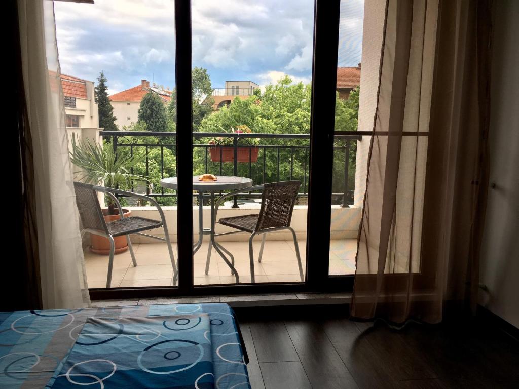 eine offene Tür zu einem Balkon mit einem Tisch und Stühlen in der Unterkunft Sarafovo Sea & Forest in Burgas City