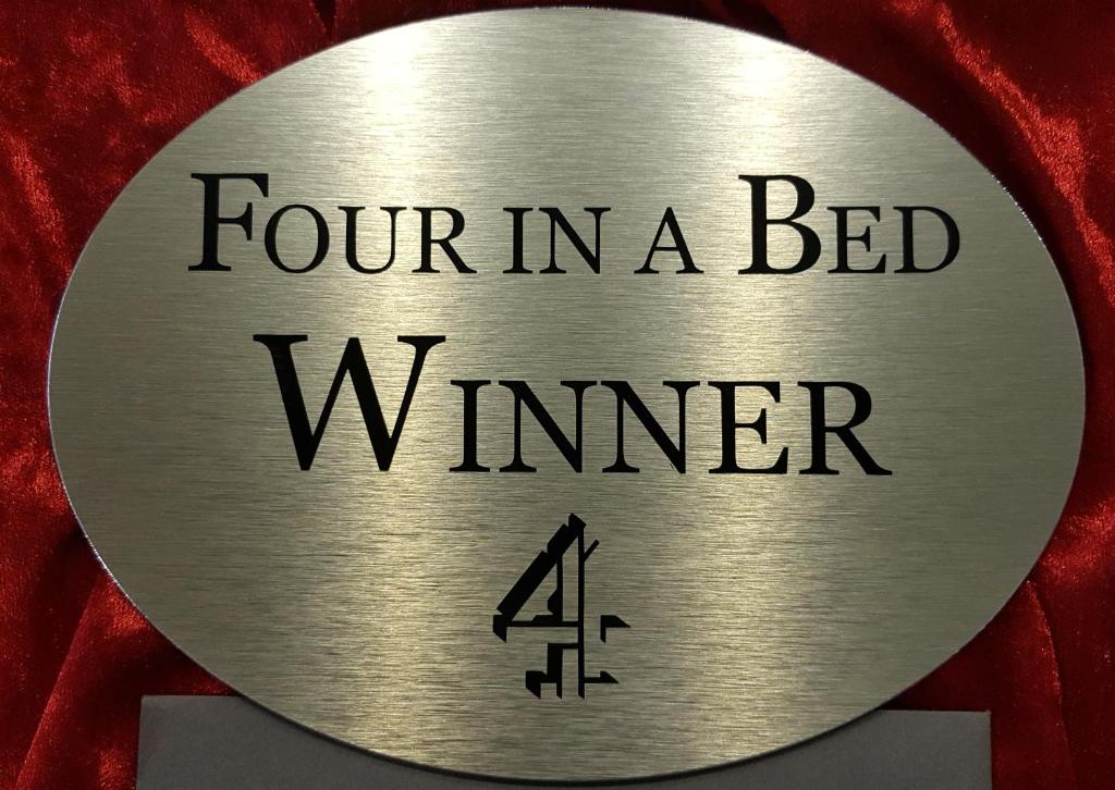 a metal medal with the text four in a bed winner at Angel Guesthouse in Tiverton