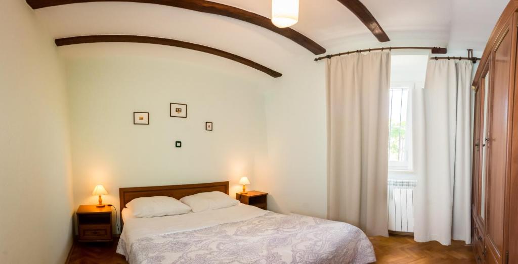 een slaapkamer met een bed, 2 lampen en een raam bij Villa Melita in Opatija