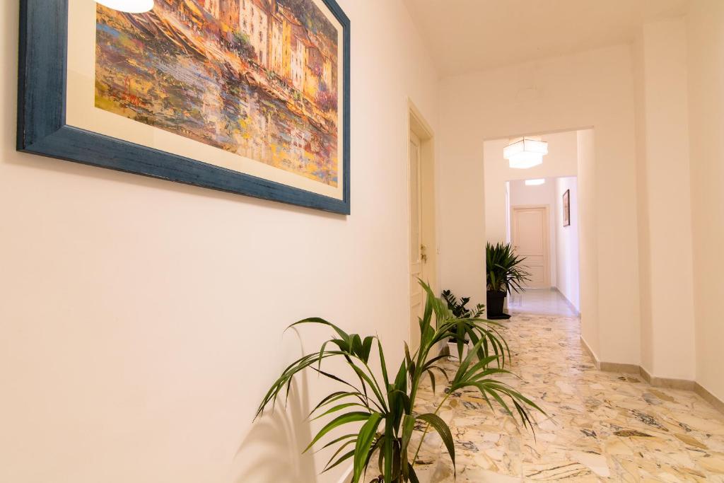 a hallway with a painting on the wall and a plant at Maison Ortigia in Syracuse