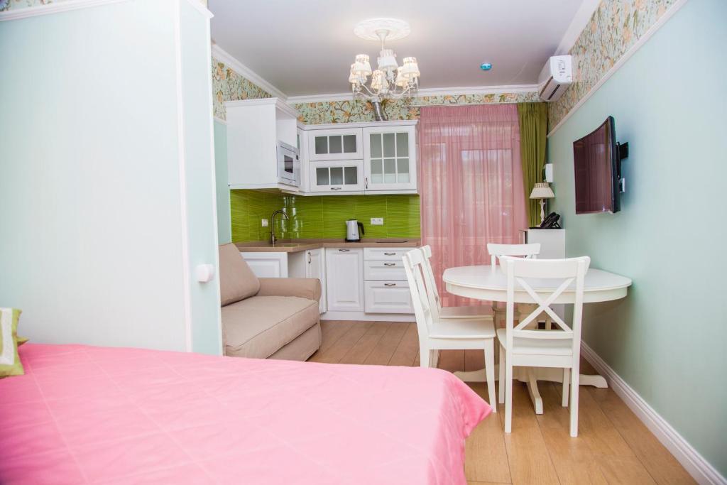 a bedroom with a pink bed and a table and chairs at Khosta Garden Hotel in Khosta