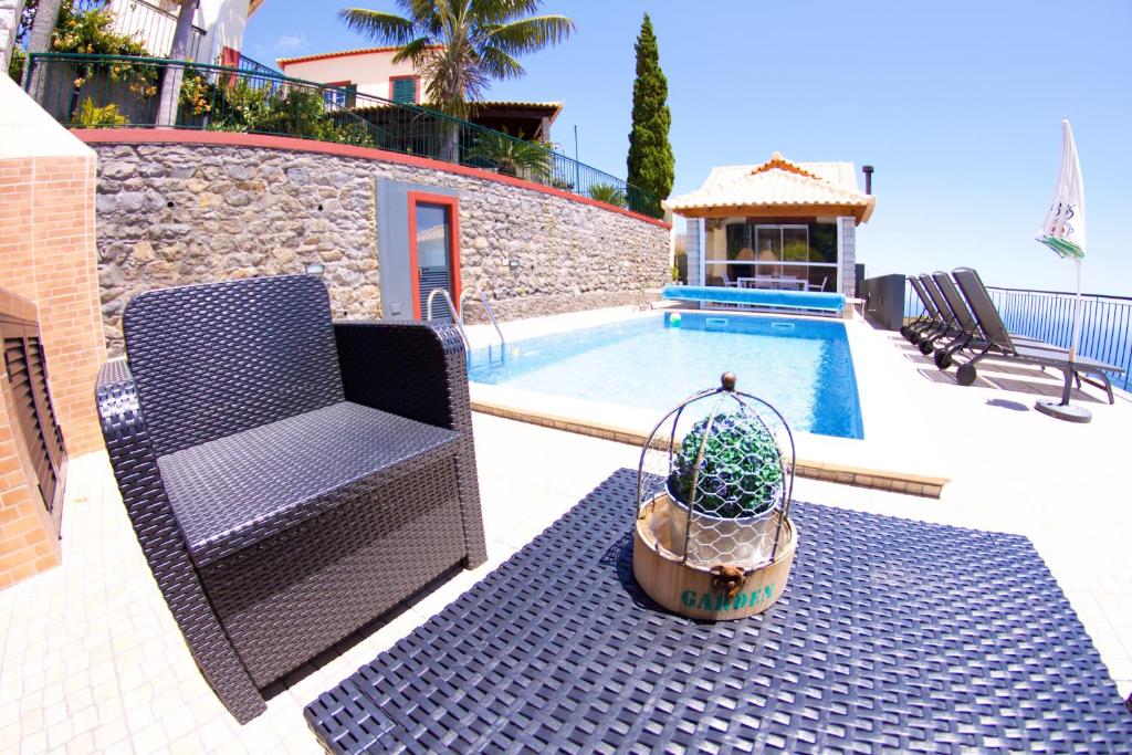 a chair and a potted plant next to a pool at Casa da Rainha Bungallow in Estreito da Calheta