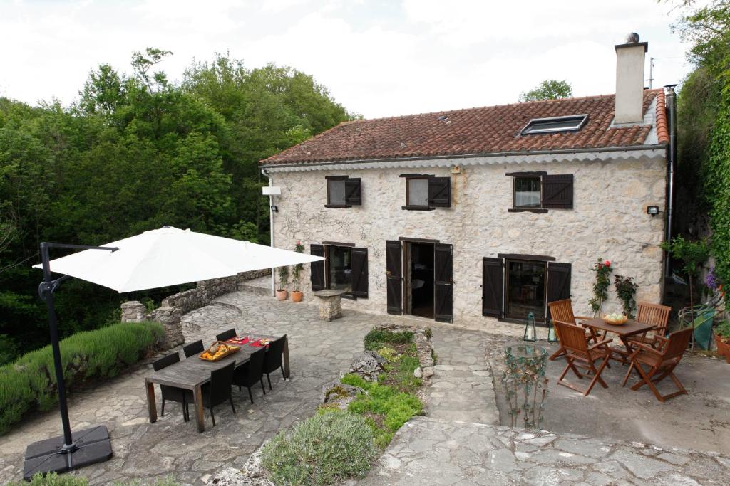 ein Steinhaus mit einem Sonnenschirm und einer Terrasse in der Unterkunft Moulin d'entre les roches in Puivert