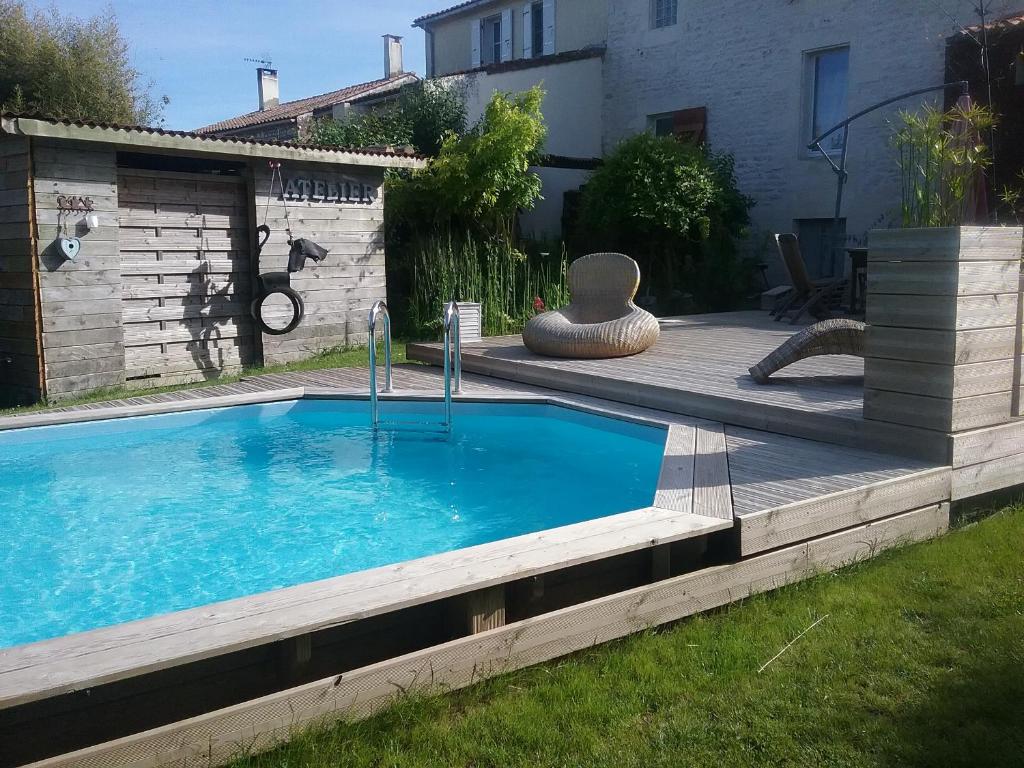 a swimming pool in a yard with a wooden deck at B&B Le verger in Échillais