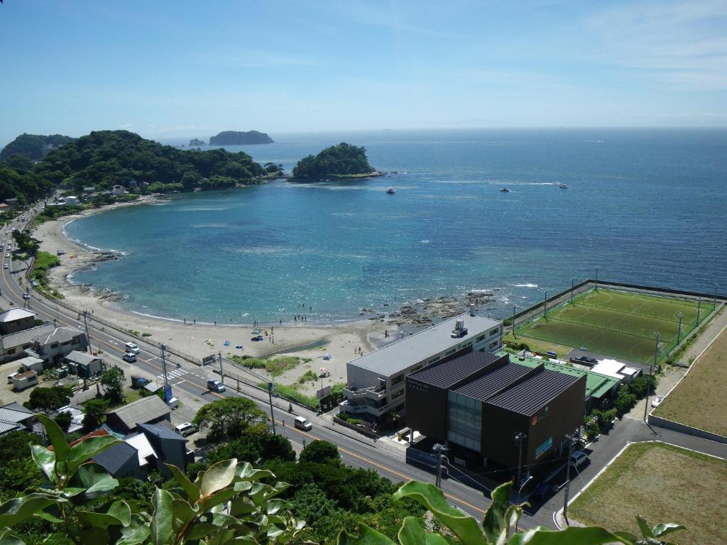 uma vista para uma praia com um edifício e um campo de ténis em Sunset Breeze Hota em Kyonan