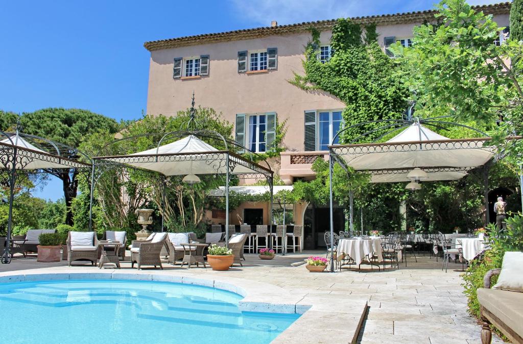 a pool with tables and chairs and a building at Mas De Chastelas in Saint-Tropez