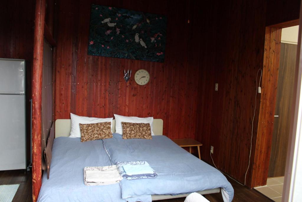 a bedroom with a bed with a clock on the wall at Guest House Miyakojima in Miyako-jima