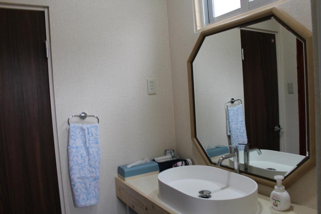 a bathroom with a sink and a large mirror at Guest House Miyakojima in Miyako-jima