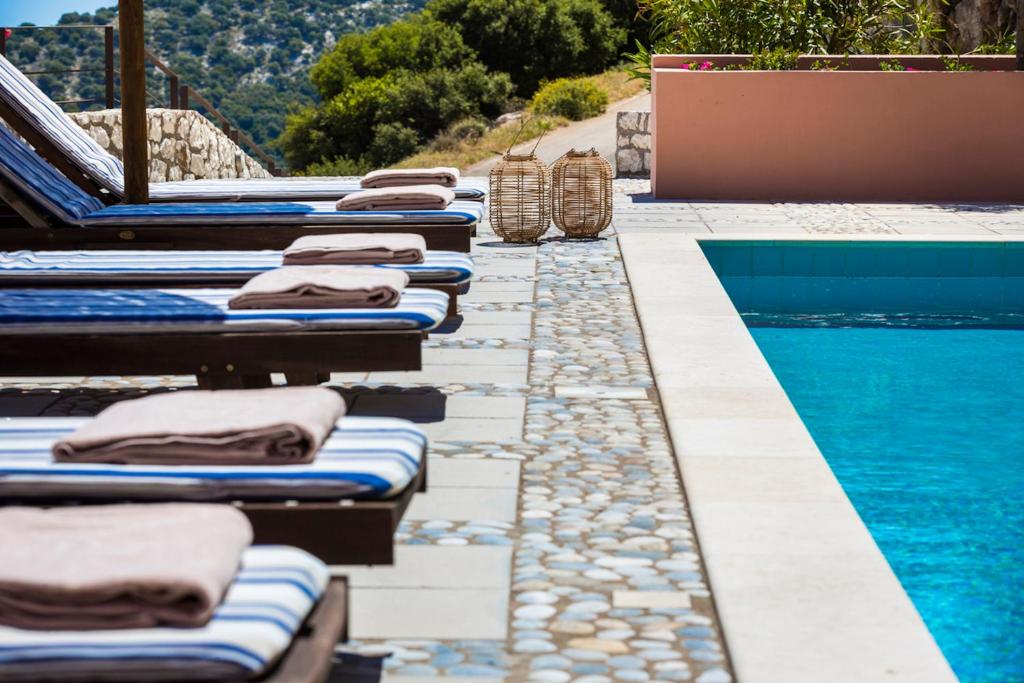 eine Reihe von Chaiselongues neben einem Pool in der Unterkunft Villa Daphni in Ayia Evfimia