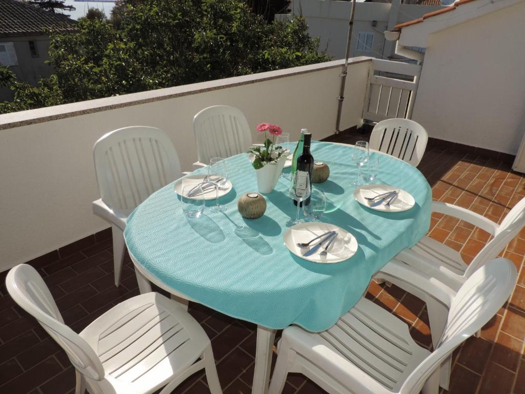 a blue table with white chairs and a bottle of wine at Apartment Vidas in Novalja